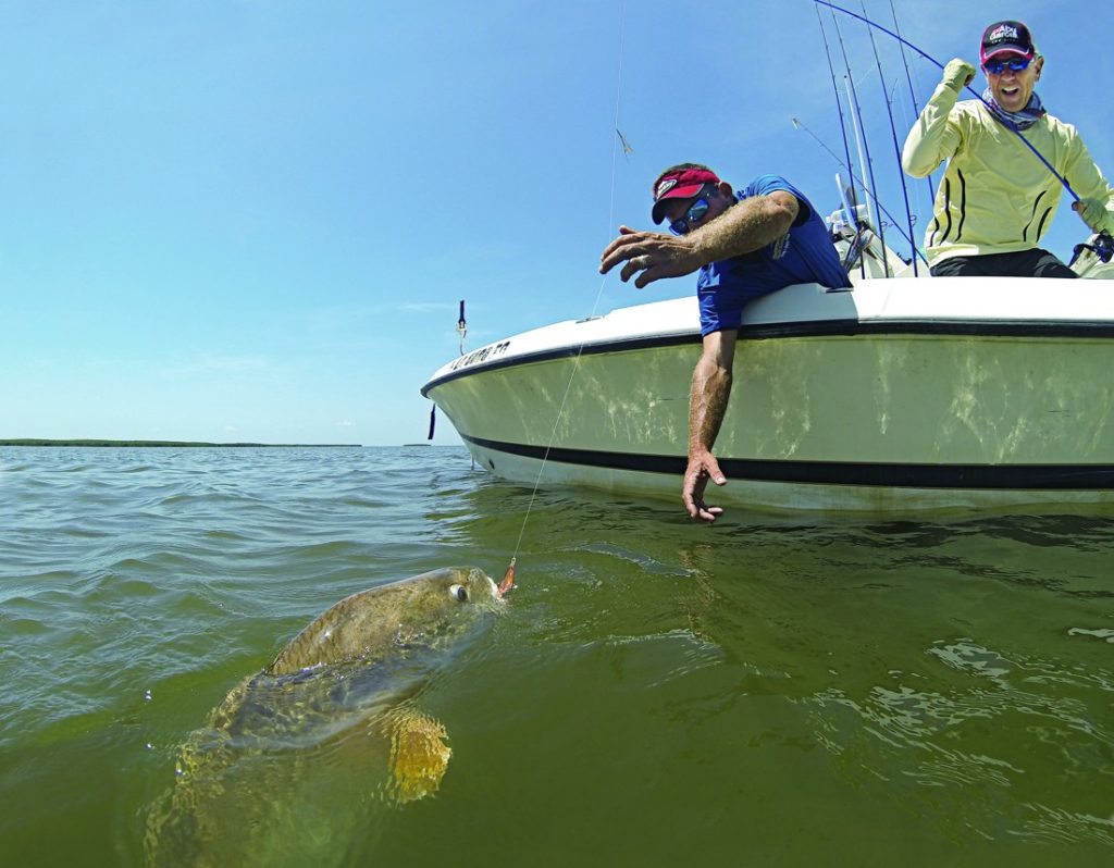 Two anglers fishing with a redfish boatside