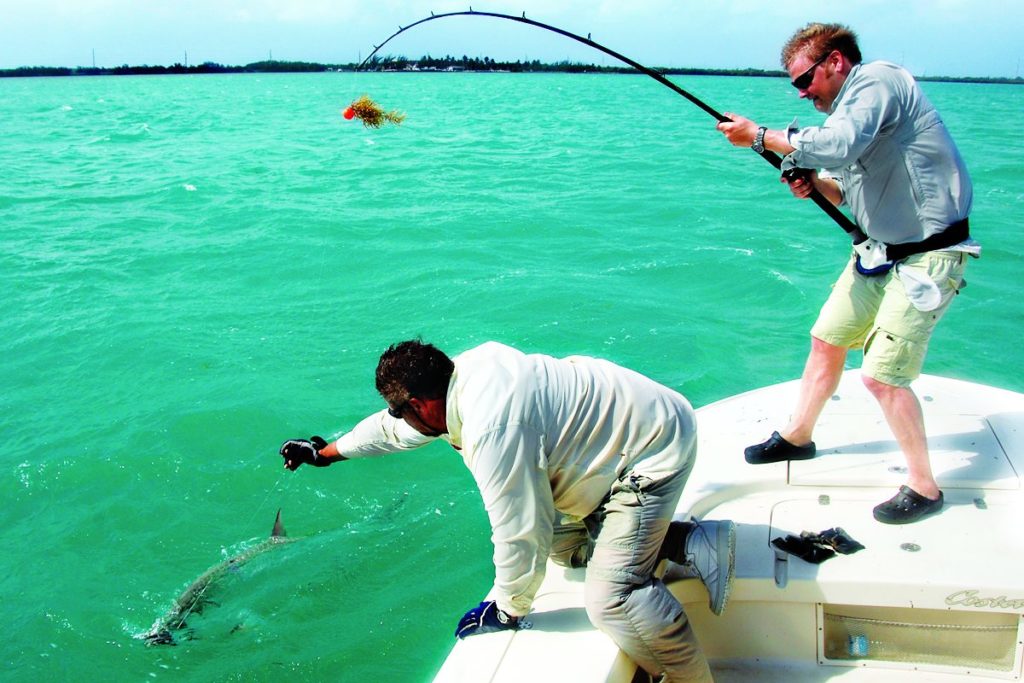 Anglers boating a fish caught on a fishing boat