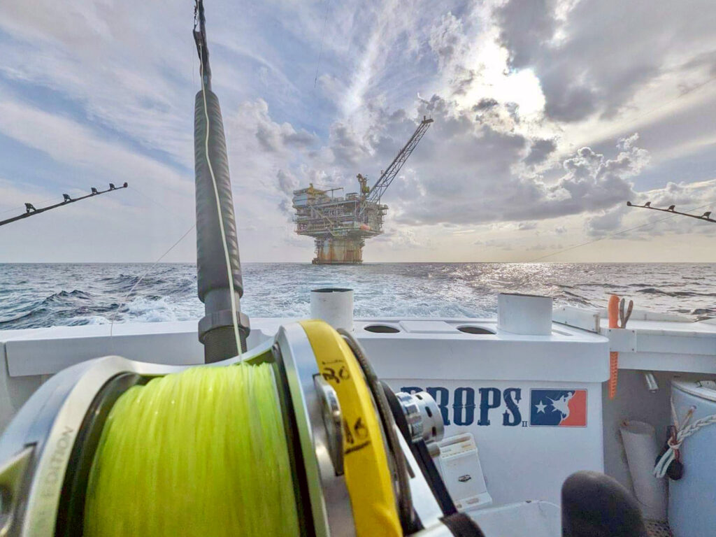 The view from the back deck of a sportfisher running away from a Texas oil rig in the distance.